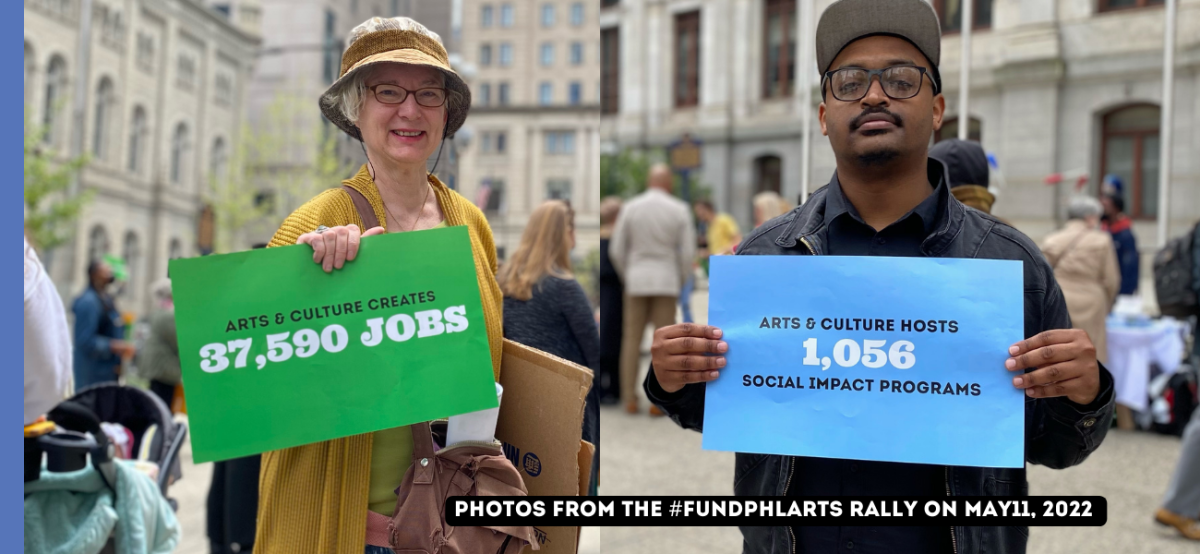On the left, a woman in a hat, glasses and yellow cardigan stands outside of City Hall in Philadelphia. She is smiling and holding a green sign that says, "Arts & culture creates 37,590 jobs." Next to her is a man in a hat and glasses who is holding a sign that says, "Arts & Culture hosts 1,056 social impact programs'