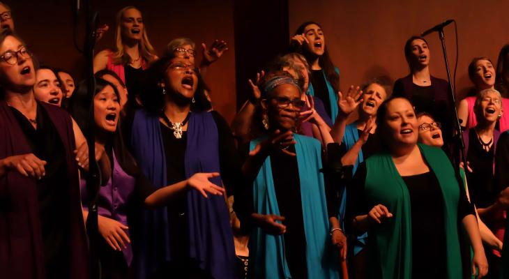 Large choir singing at a concert in colorful vests