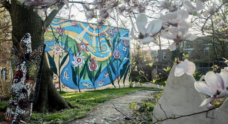 The Village's Ile Ife Park with murals and mosaics in the background and a blooming magnolia tree in the foreground