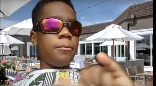 A young, Black boy, wearing sunglasses, who is part of the AWB Juniors Program